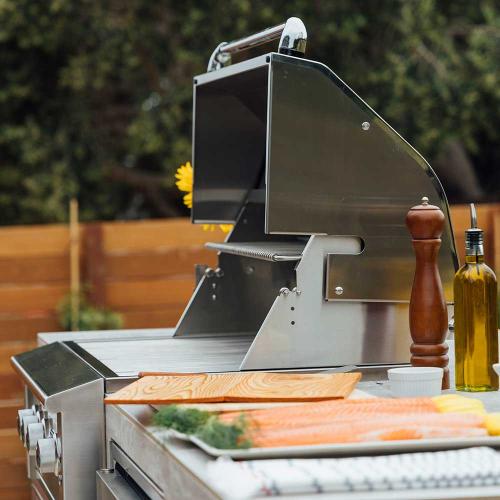 Metallic slicer on a table with vegetables and a bottle of oil outdoors