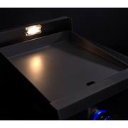 Stainless steel griddle with glowing element on a dark background