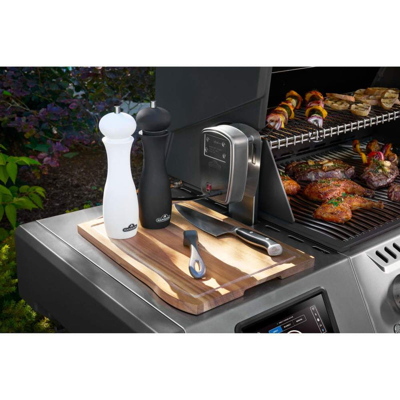Grill with cutting board, knives, and seasoning shakers on a barbecue scene