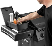 Person using a portable grill with a storage compartment.