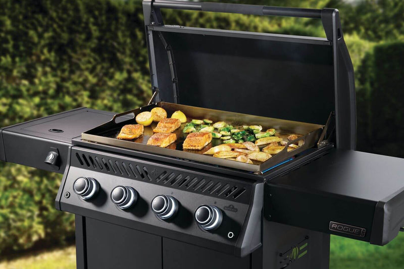 Black grill with food on a green outdoor background