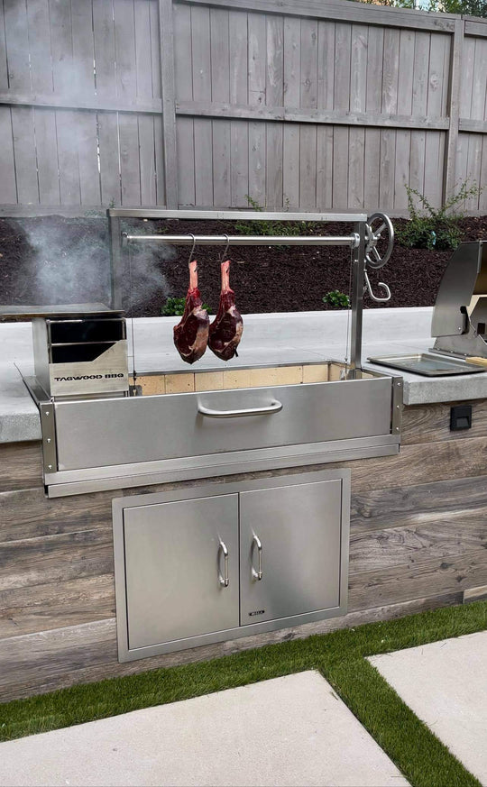 Stainless steel outdoor grill with hanging meat on a wooden deck
