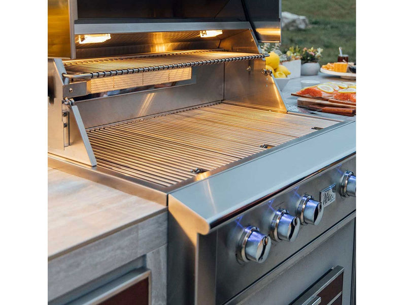 Stainless steel grill with open lid on a patio with food and people in the background